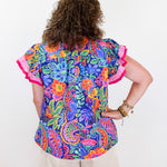 Person wearing a colorful floral blouse with ruffled sleeves on a white background