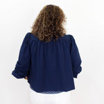 Person wearing a navy blue blouse with long sleeves on a white background