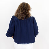 Person wearing a navy blue blouse with long sleeves on a white background