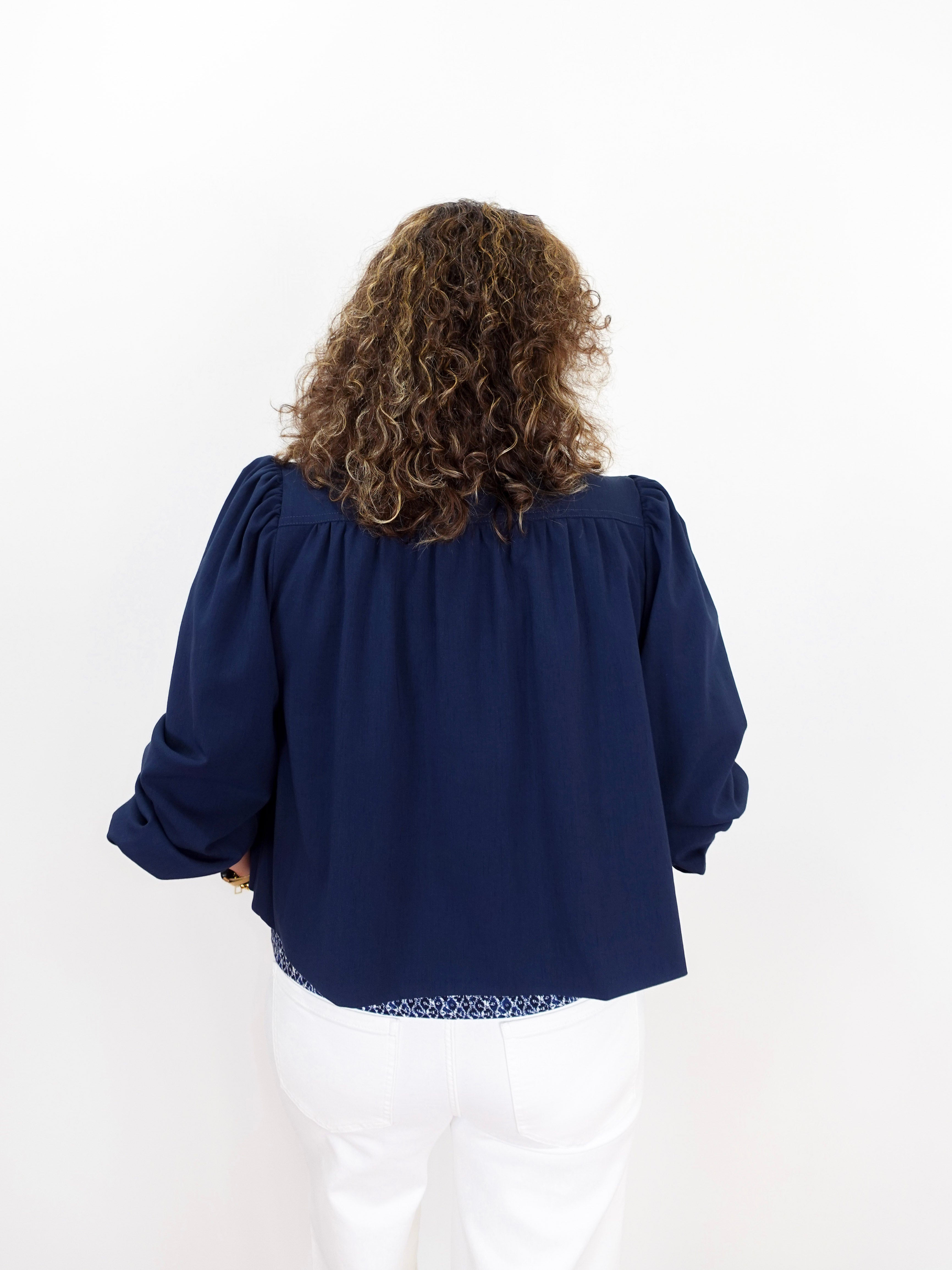Person wearing a navy blue blouse with long sleeves on a white background