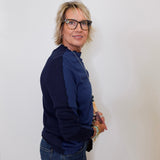 Person wearing a navy blue sweater and jeans against a white background