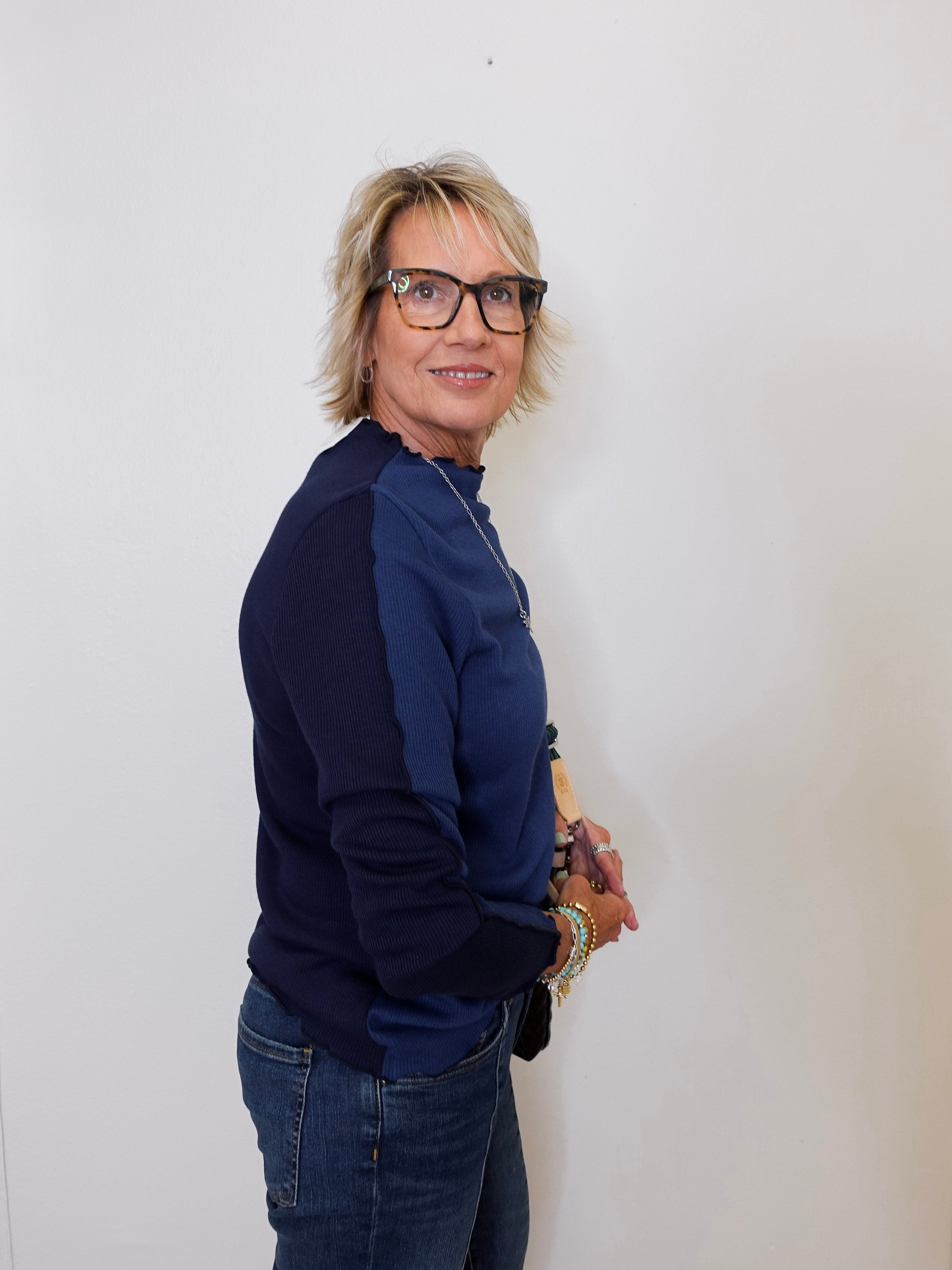 Person wearing a navy blue sweater and jeans against a white background