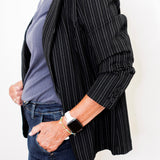 Person wearing a black pinstripe blazer over a blue shirt with a white background