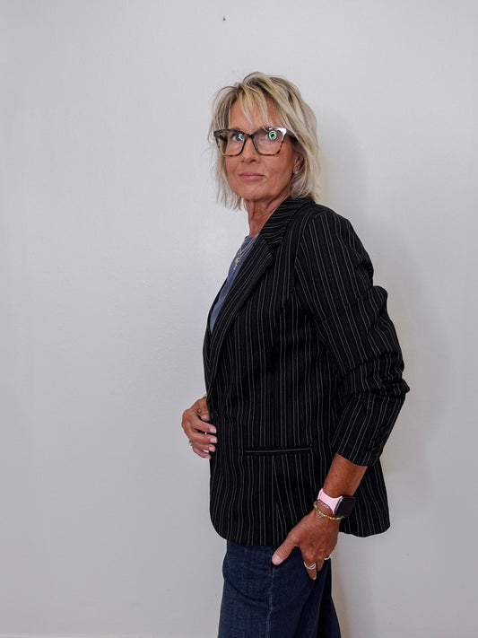 Person wearing a black pinstripe blazer against a plain background