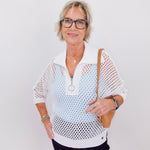 Woman wearing a white mesh top with a plain background