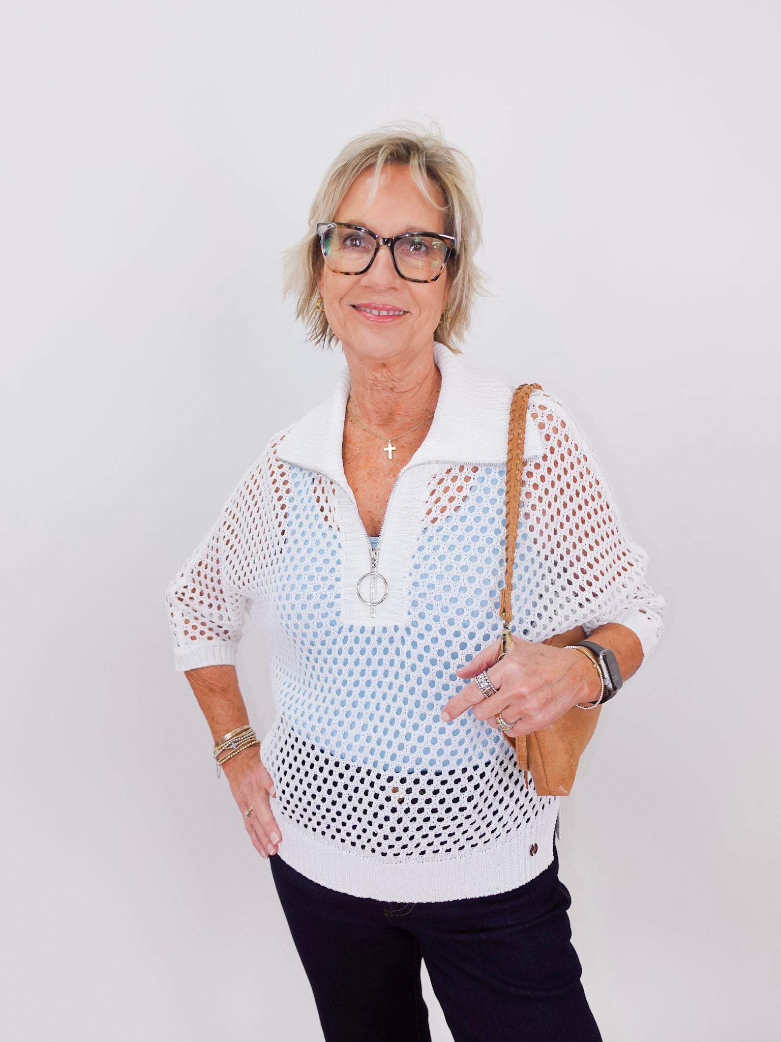 Woman wearing a white mesh top with a plain background