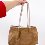 Hand holding a woven handbag against a white background