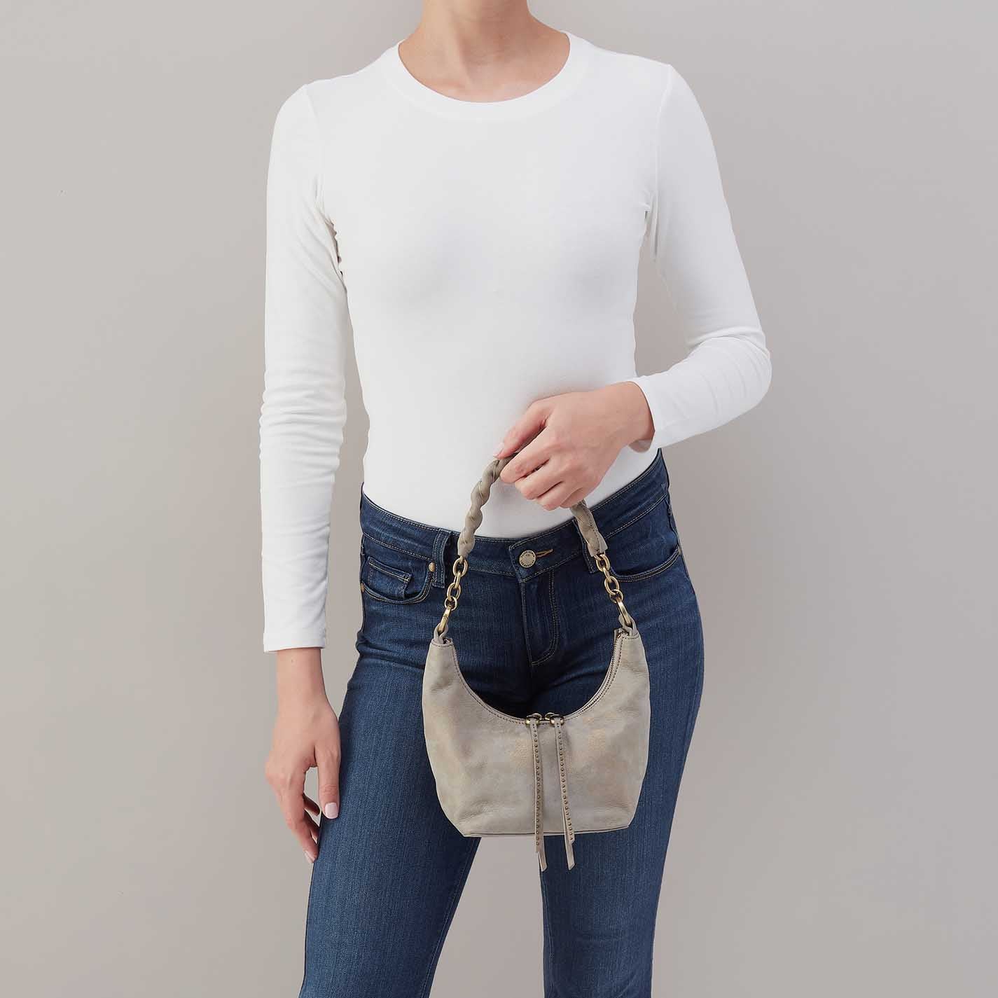 Person holding a beige handbag against a plain background