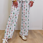 Person wearing a festive pajama set with various patterns on a wooden floor.