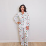 Woman wearing a patterned pajama set against a white wall.