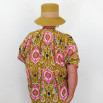 Person wearing a patterned shirt and hat against a white background