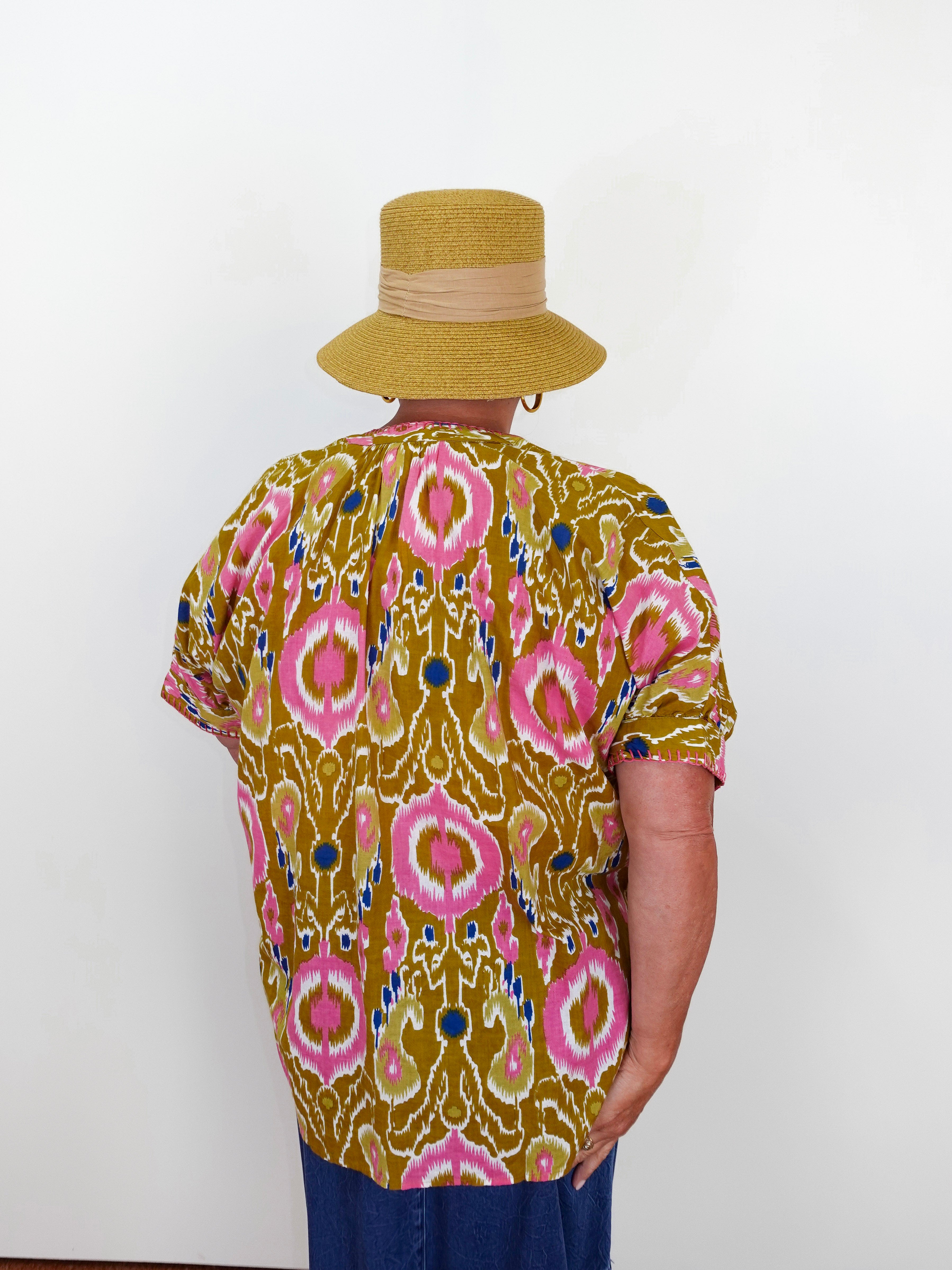 Person wearing a patterned shirt and hat against a white background