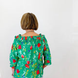 Person wearing a green floral blouse against a white background