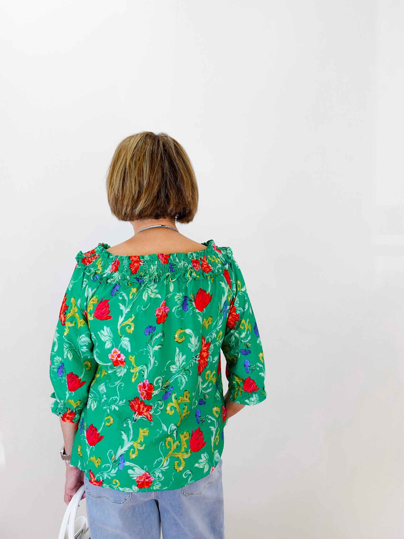 Person wearing a green floral blouse against a white background