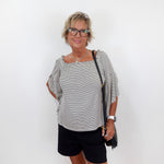 Woman wearing a black and white striped top and black shorts against a white background