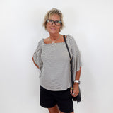 Woman wearing a black and white striped top and black shorts against a white background