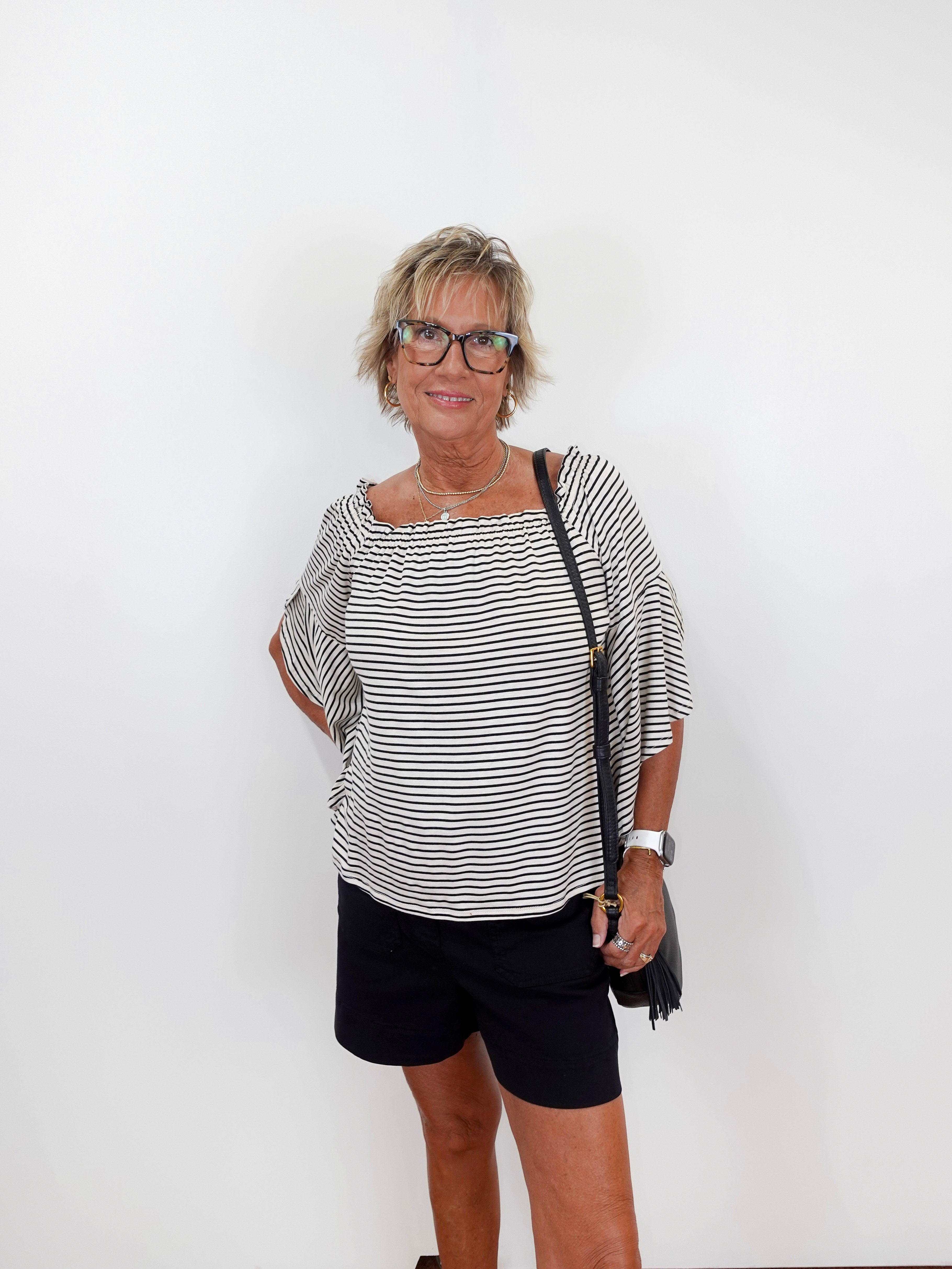 Woman wearing a black and white striped top and black shorts against a white background