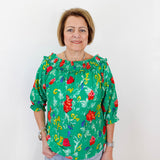 Woman wearing a green floral blouse against a white background