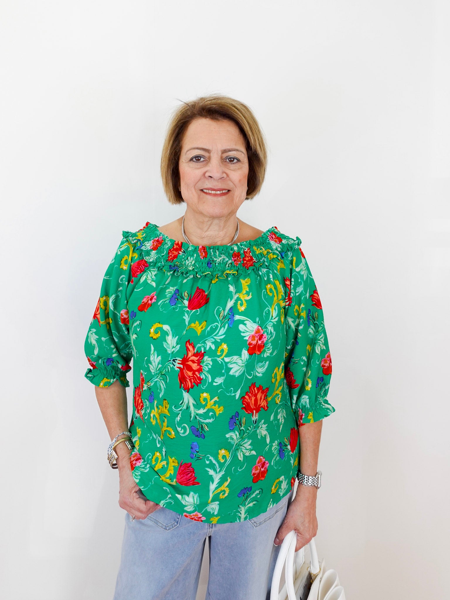 Woman wearing a green floral blouse against a white background