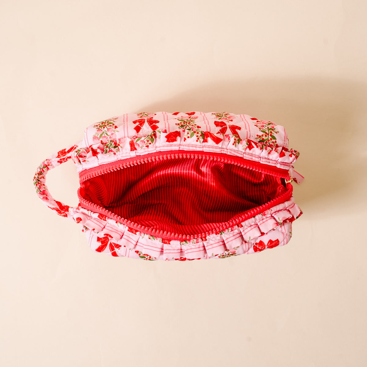 Pink pouch with floral patterns on a beige background