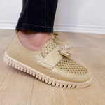 A person modeling a the ilse Jacobsen tassel loafer in gold against a white wall.