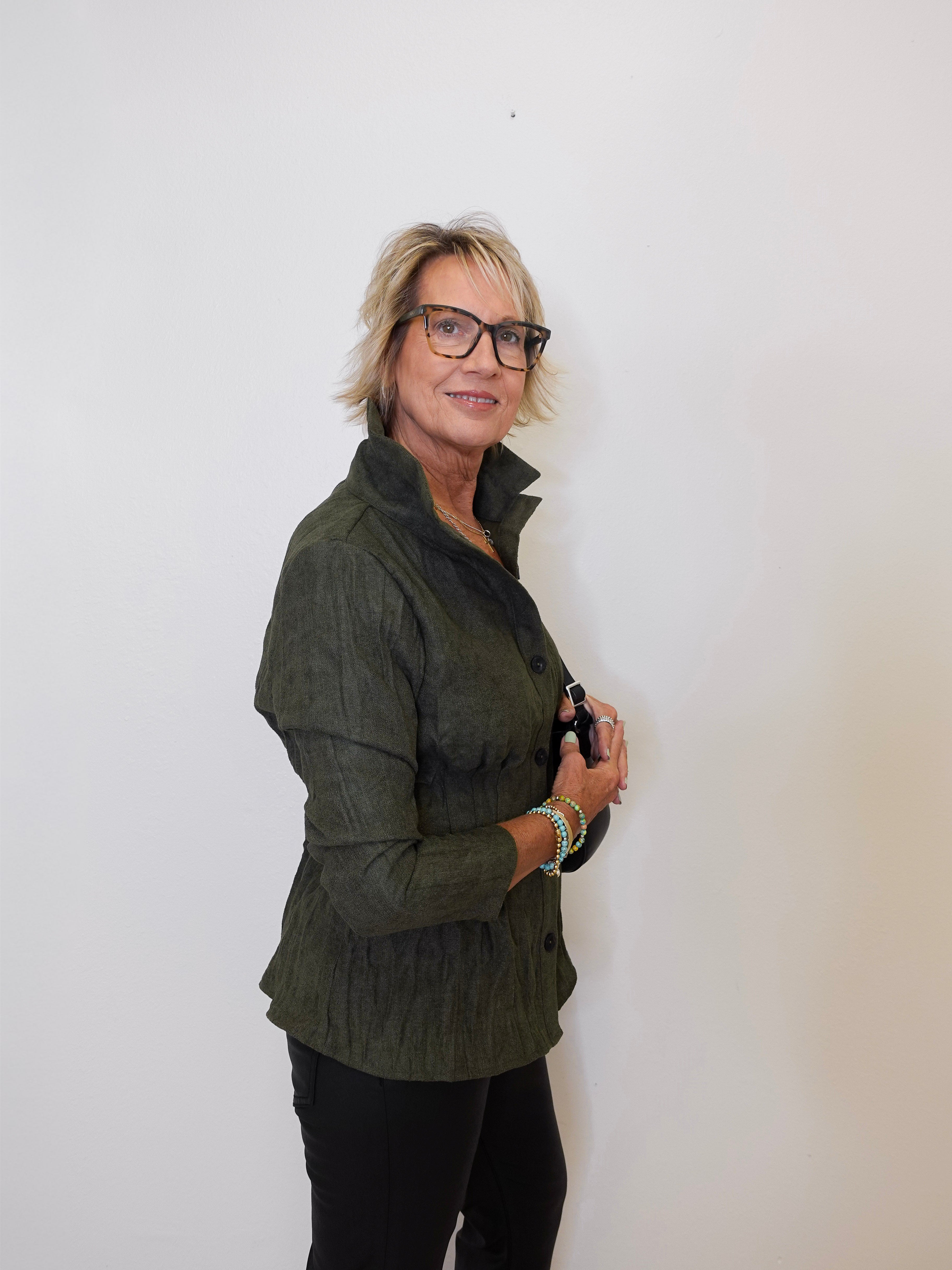 Person wearing a green jacket and black pants against a white background