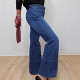 A woman modeling French dressing jeans the olivia bootleg jean against a white wall. 