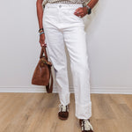 Person wearing a striped shirt, white pants, and brown shoes on a wooden floor.