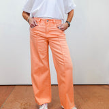 Person wearing peach-colored pants and a white shirt against a plain background