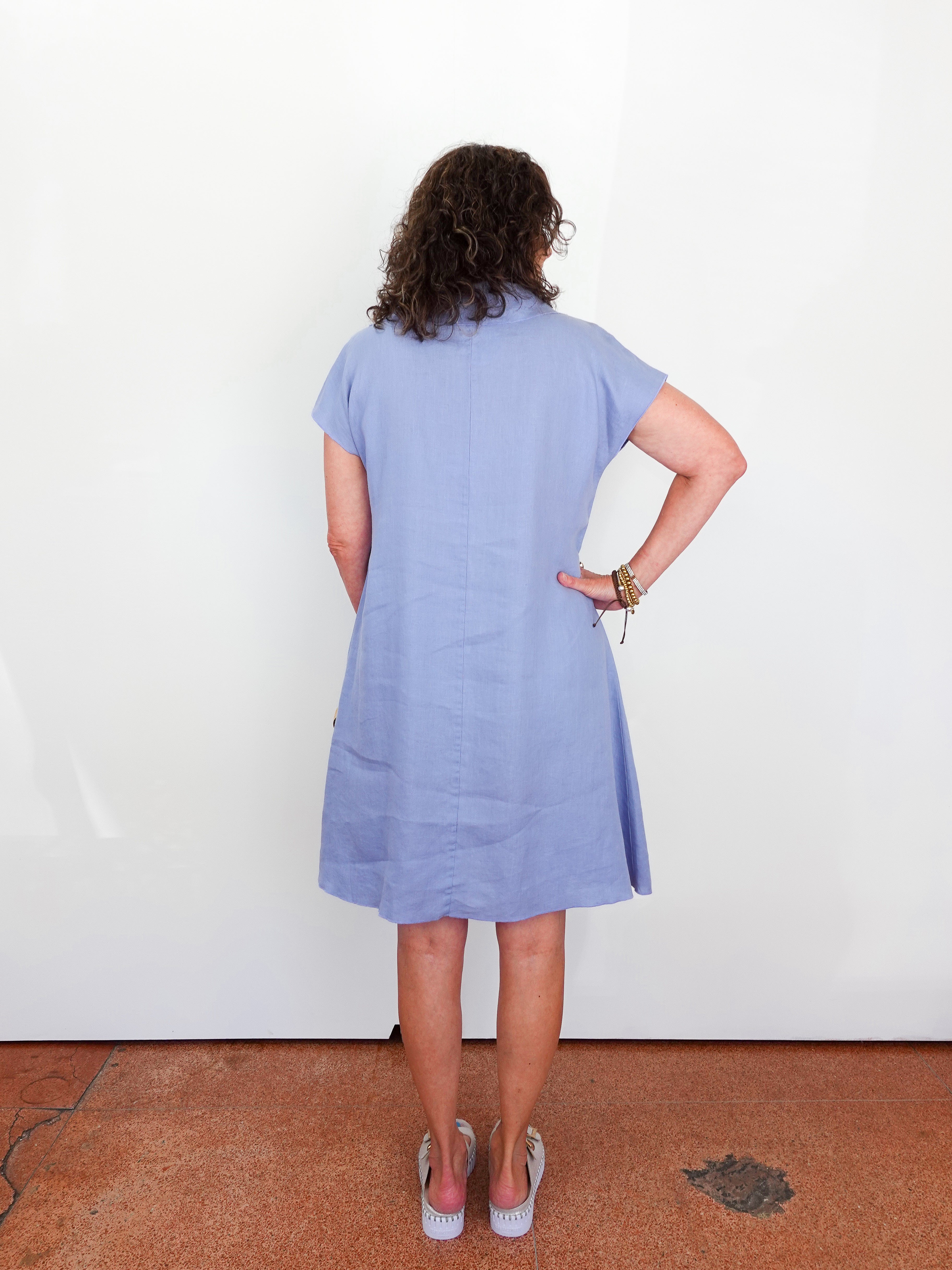 Person wearing a light blue dress standing against a white wall.