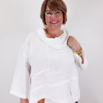 Woman wearing a white poncho against a plain background