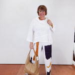 Woman holding a beige handbag against a white wall