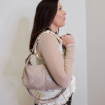 women wearing a hobo opal mini shoulder bag against a white background. 