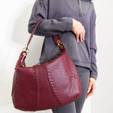 Person holding a maroon handbag against a white background