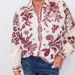 Woman wearing a floral patterned blouse with red designs on a white background