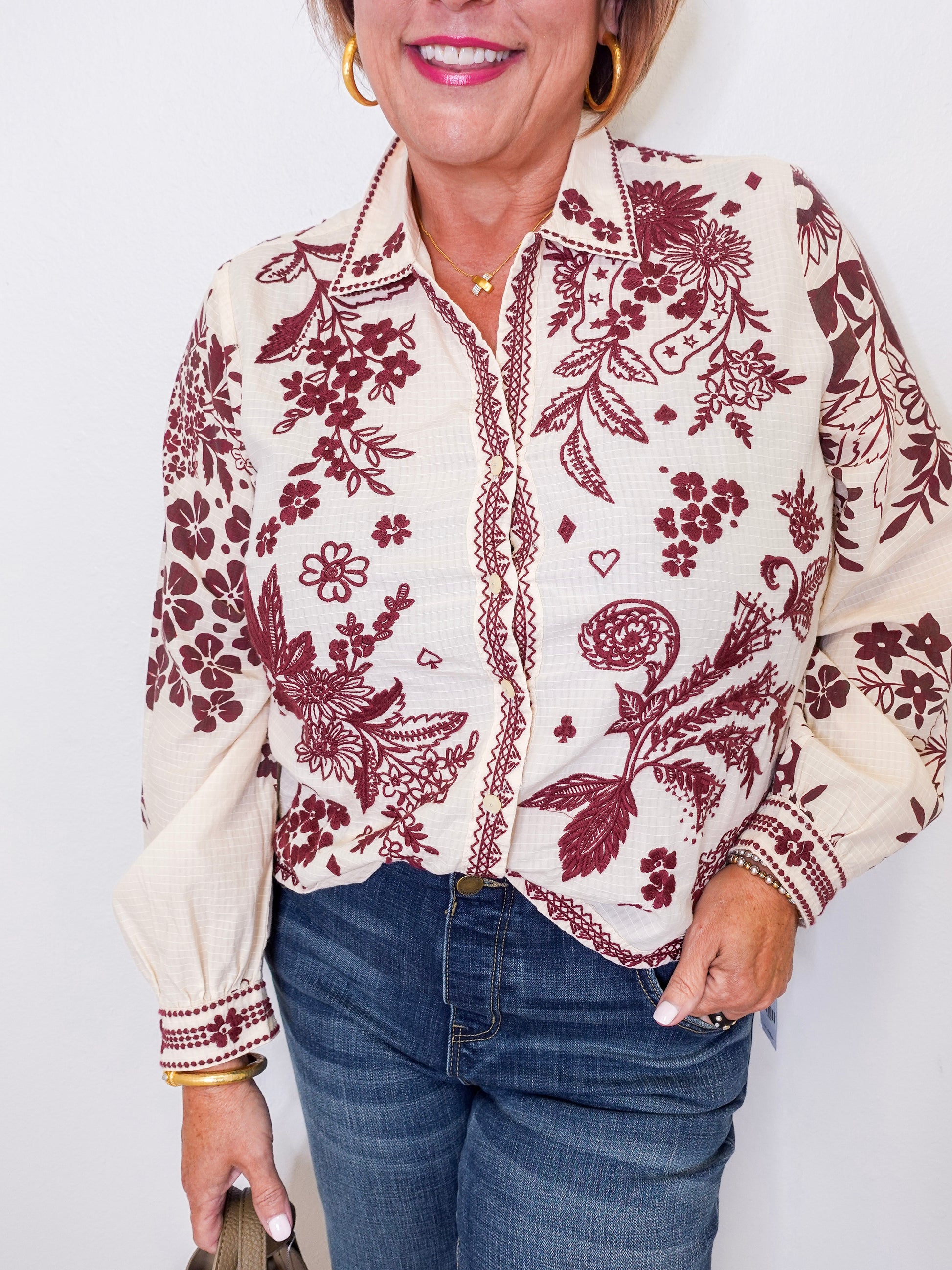 Woman wearing a floral patterned blouse with red designs on a white background