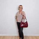 Woman holding a red handbag against a white wall