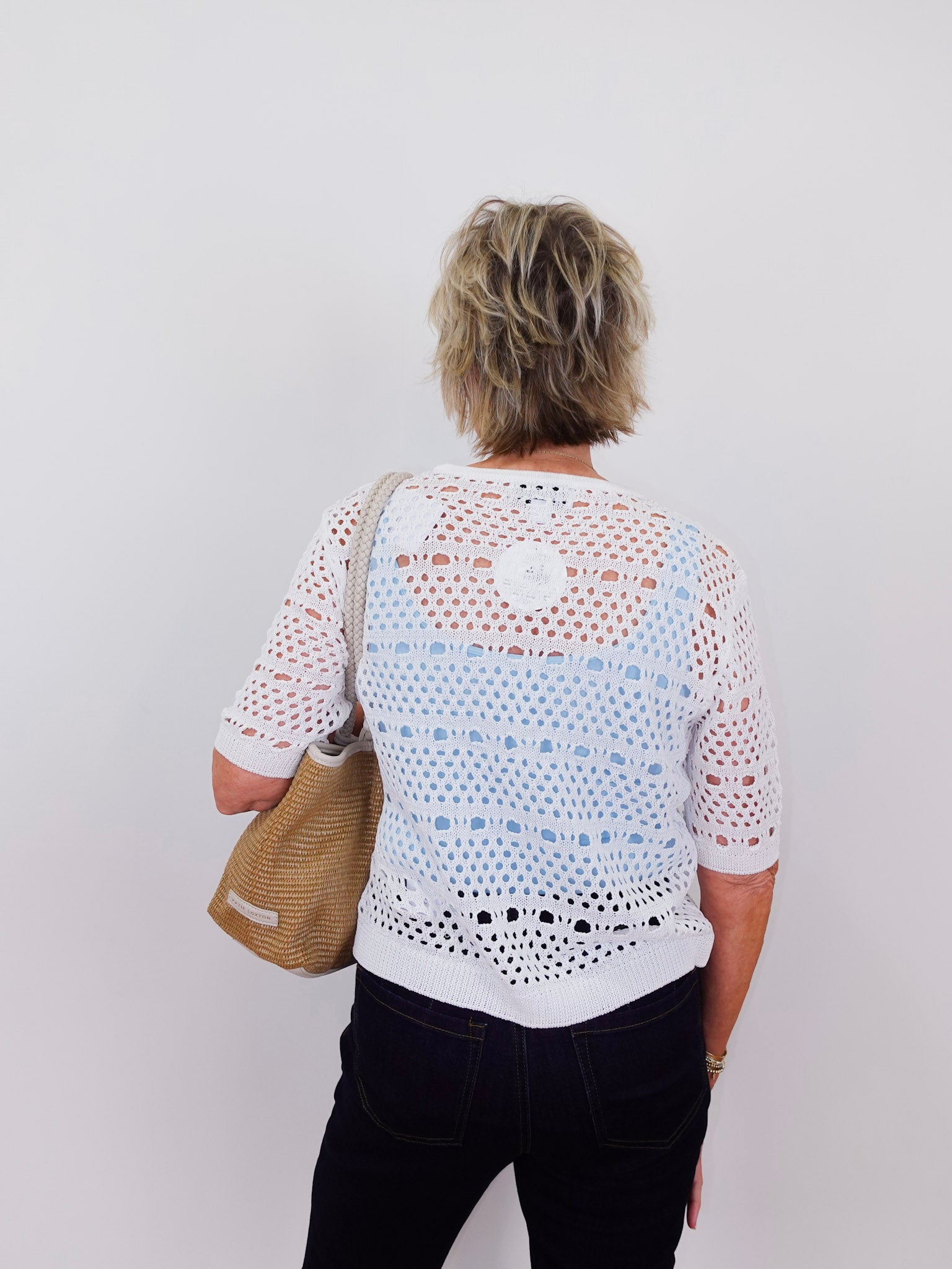 Person wearing a white lace top with a plain background