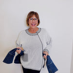 Woman holding denim jackets against a white background