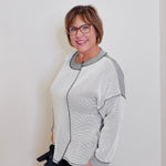 Woman wearing a gray and white patterned cardigan against a white background