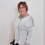 Woman wearing a gray and white patterned cardigan against a white background