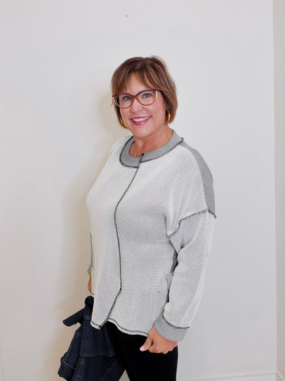 Woman wearing a gray and white patterned cardigan against a white background
