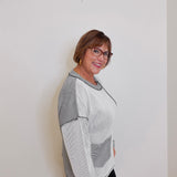 Person wearing a gray and white sweater against a plain background