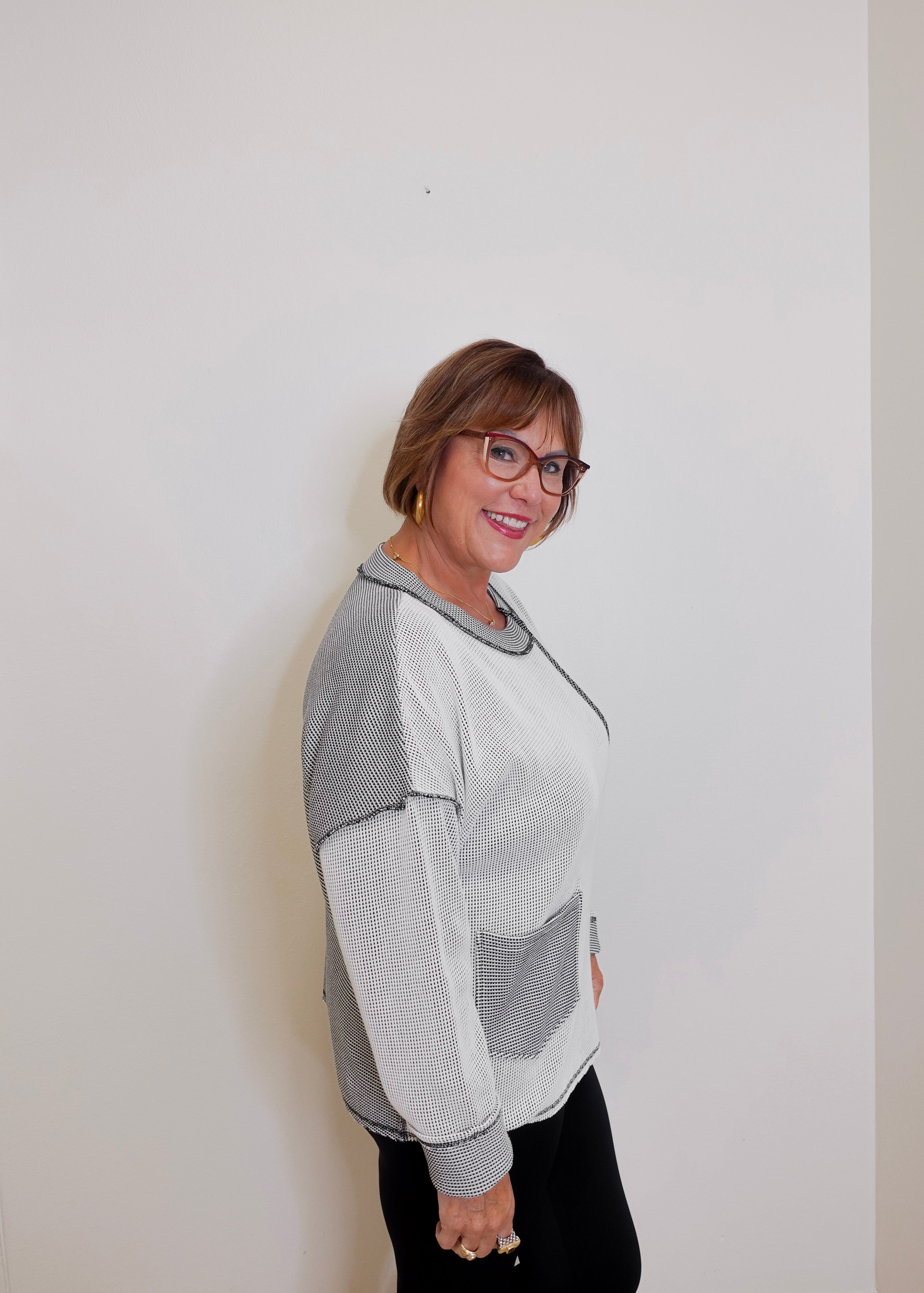Person wearing a gray and white sweater against a plain background