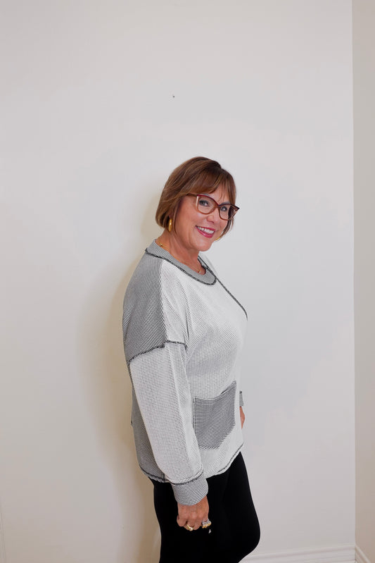 Person wearing a gray and white sweater against a plain background