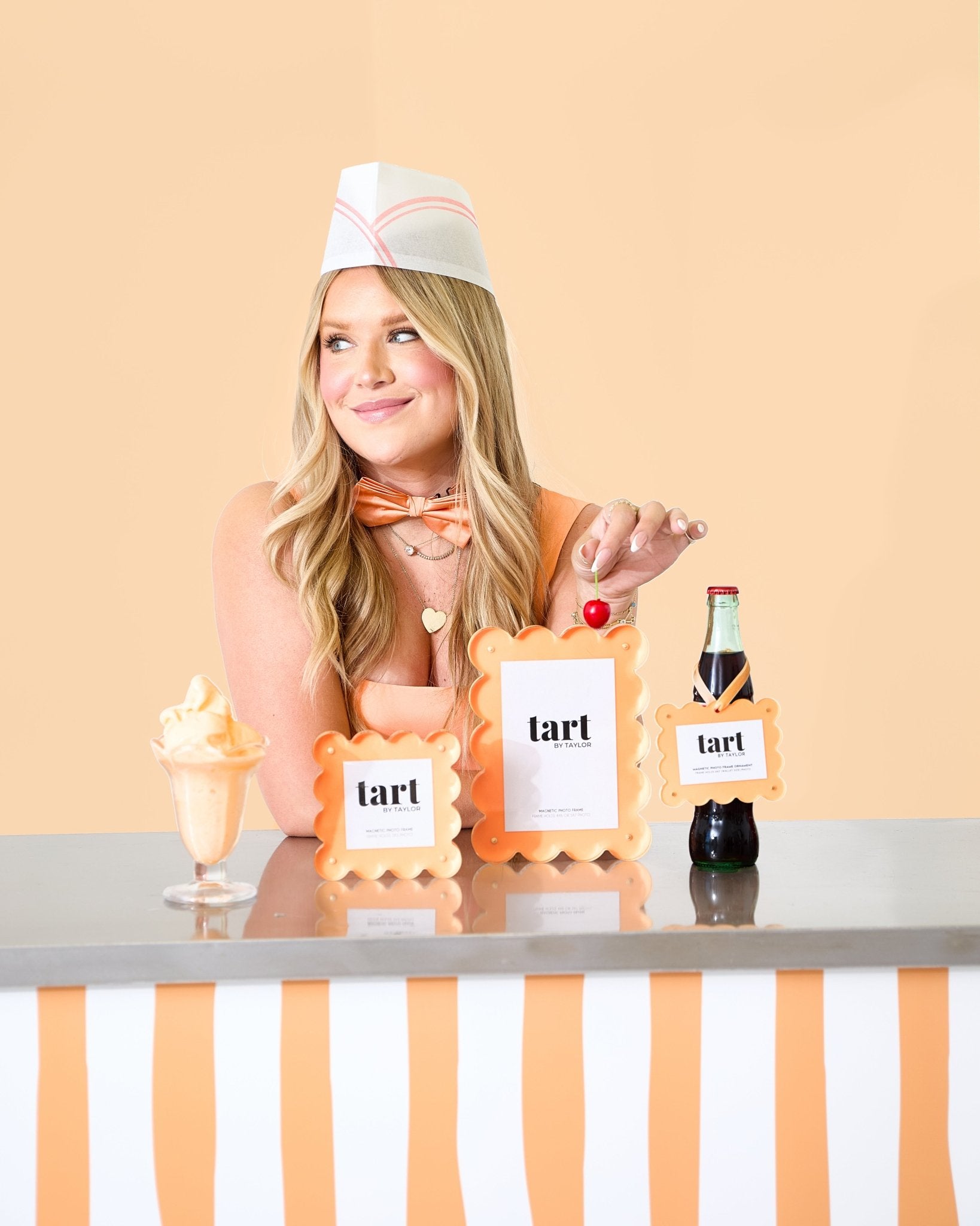 Person in a dessert-themed costume with props on a table against a beige background