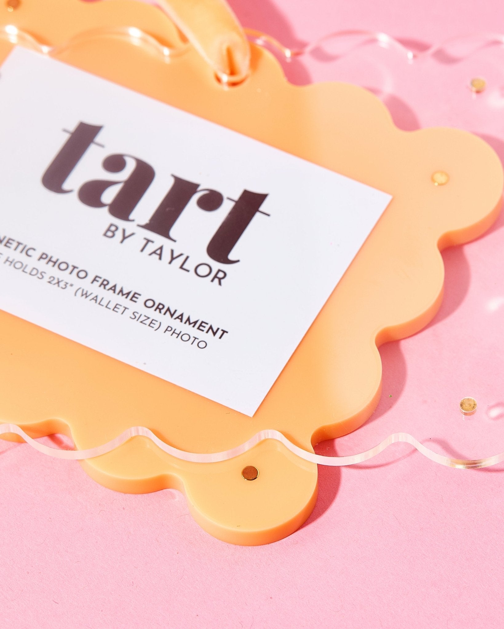 Orange photo frame ornament with a label on a pink background