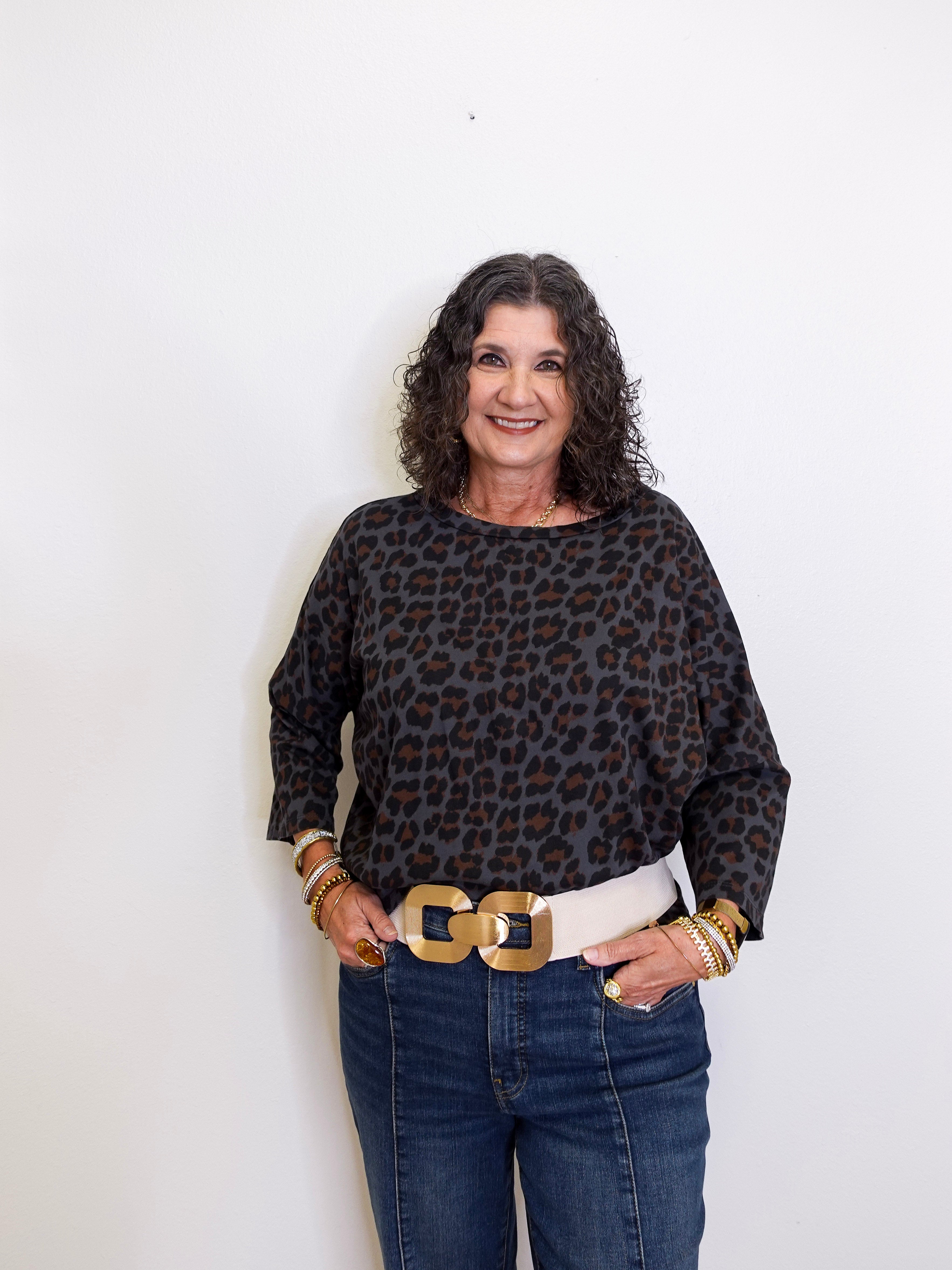 Woman wearing a leopard print top and jeans with a white background