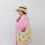 Person wearing a straw bag with colorful designs against a white background