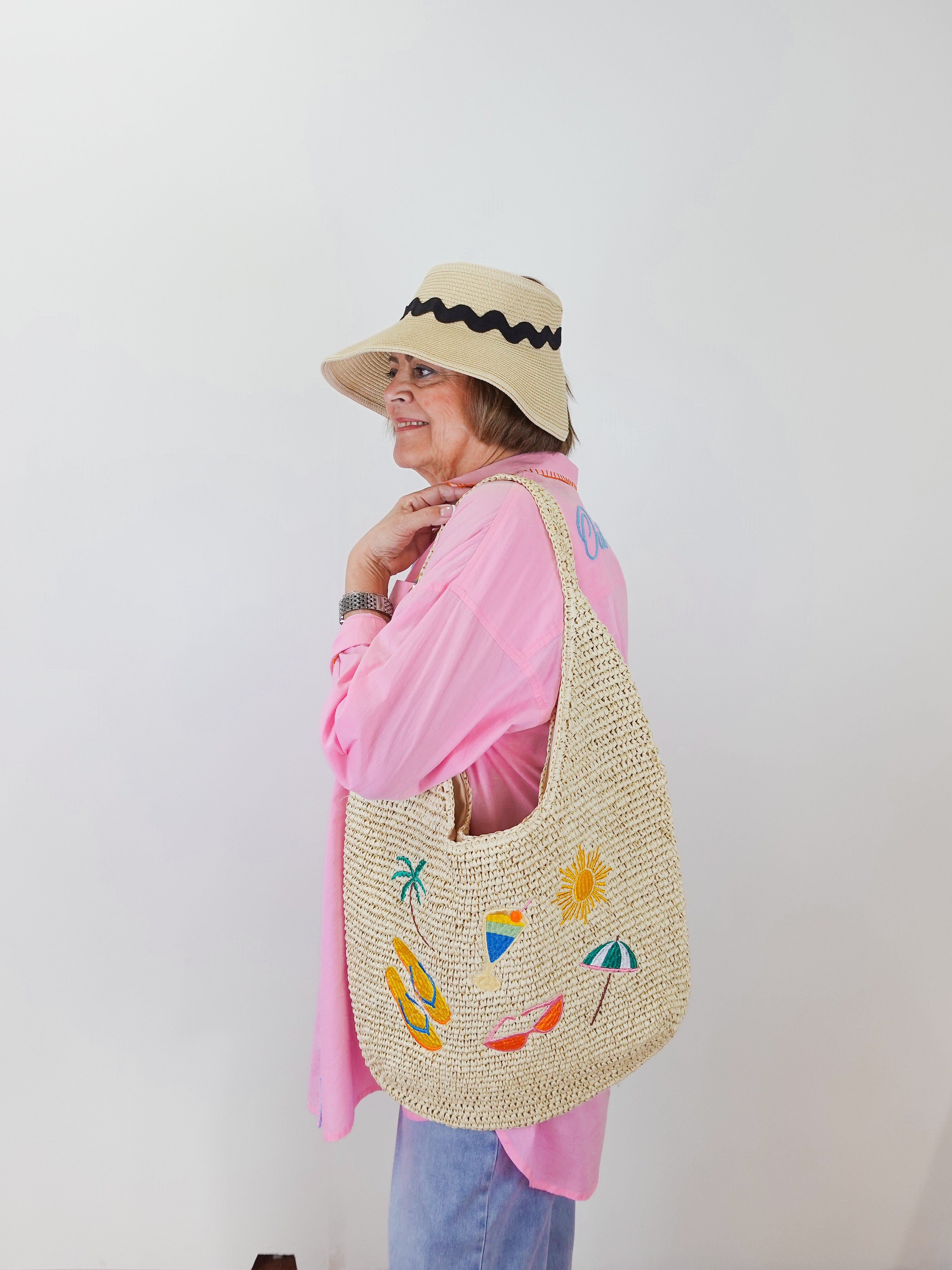Person wearing a straw bag with colorful designs against a white background